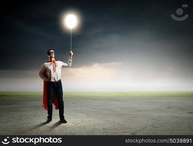 Superman with balloon. Young man in superhero costume holding balloon in hand