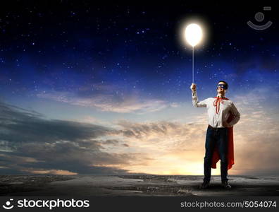 Superman with balloon. Young man in superhero costume holding balloon in hand