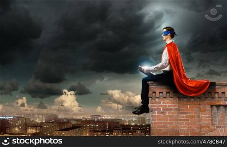 Superman with book. Young man in superhero costume reading book