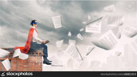 Superman with book. Young man in superhero costume reading book