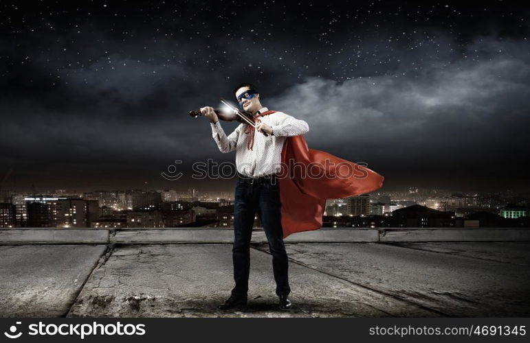 Superman with violin. Young man in superhero costume playing violin