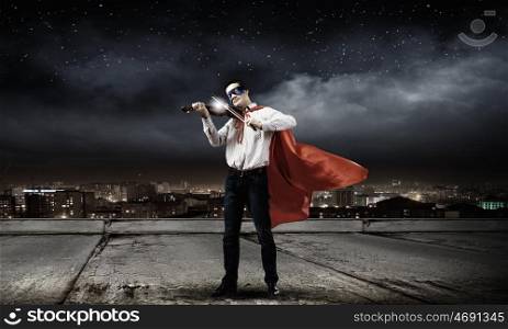 Superman with violin. Young man in superhero costume playing violin