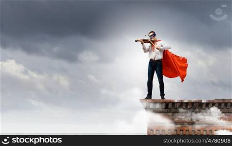Superman with violin. Young man in superhero costume playing violin
