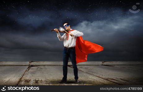 Superman with violin. Young man in superhero costume playing violin