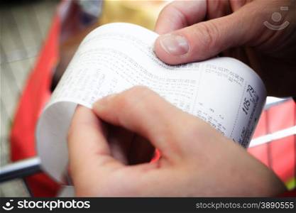 Supermarket shop. Closeup of paper check receipt bill in human hand. Paying and retail.