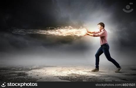 Supernormal man. Young man in casual throwing fire ball