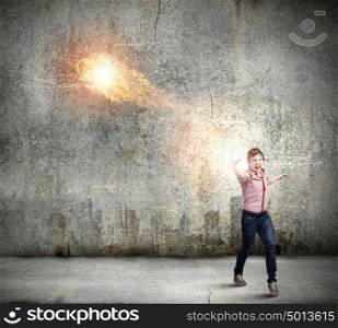 Supernormal man. Young man in casual throwing fire ball