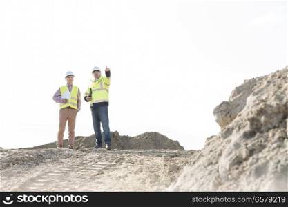 Supervisor discussing with colleague at construction site against clear sky