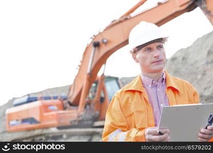 Supervisor looking away while holding clipboard at construction site