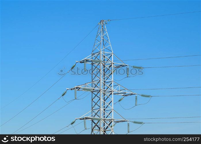 Supports high-voltage power lines against the blue sky.. Supports high-voltage power lines against the blue sky