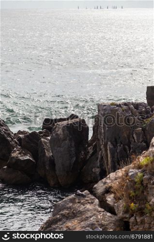 surf ocean rocks with sails on horizone