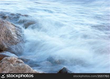 surf on rocky shore in evening