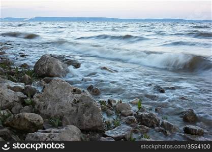 surf on rocky shore in evening