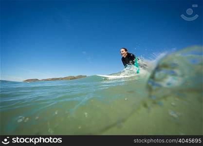 Surface level view of young woman on surfboard in ocean, Ventura, USA