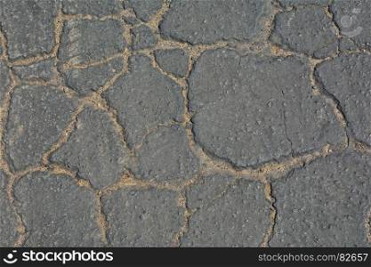 Surface of grey cracked asphalt background.