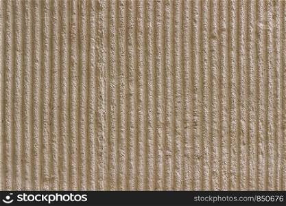 Surface of the wall with a decorative light beige plaster. Textured concrete wall with vertical lines and stripes as a texture or background. Seamless texture for background. Repair, design concept.
