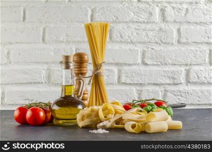 surface with different types pasta tomatoes oil