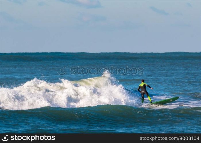 surfer black and green wetsuit riding the wave