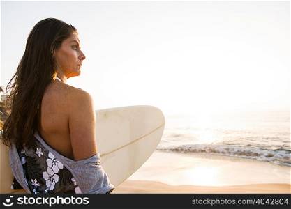 Surfer carrying surf board, looking at sea