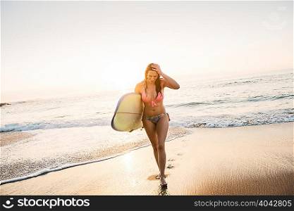 Surfer carrying surf board, out of sea