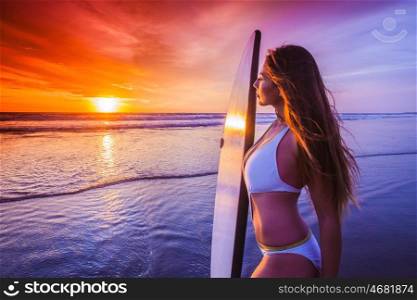 Surfer girl on beach at sunset. Beautiful sexy surfer girl on the beach at sunset