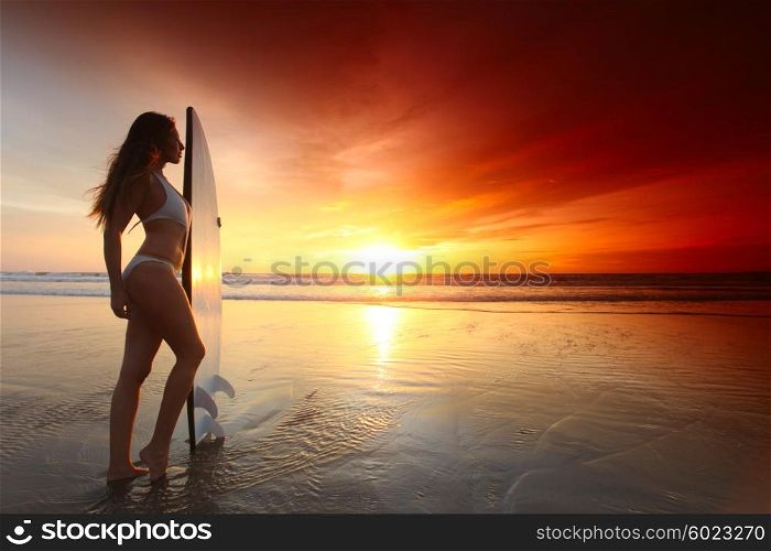 Surfer girl on beach at sunset. Beautiful surfer girl on the beach at sunset