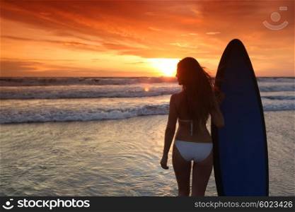 Surfer girl on beach at sunset. Beautiful surfer girl on the beach at sunset