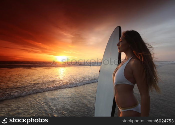 Surfer girl on beach at sunset. Beautiful surfer girl on the beach at sunset