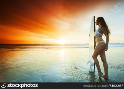 Surfer girl on the beach. Beautiful sexy surfer girl on the beach at sunset