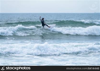 Surfer girl riding a wave on a cloudy afternoon at Torreira beach, Murtosa - Portugal.