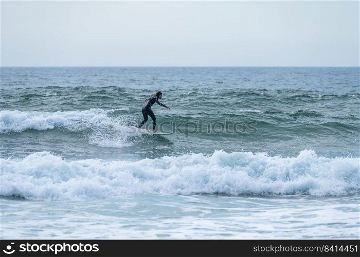 Surfer girl riding a wave on a cloudy afternoon at Torreira beach, Murtosa - Portugal.