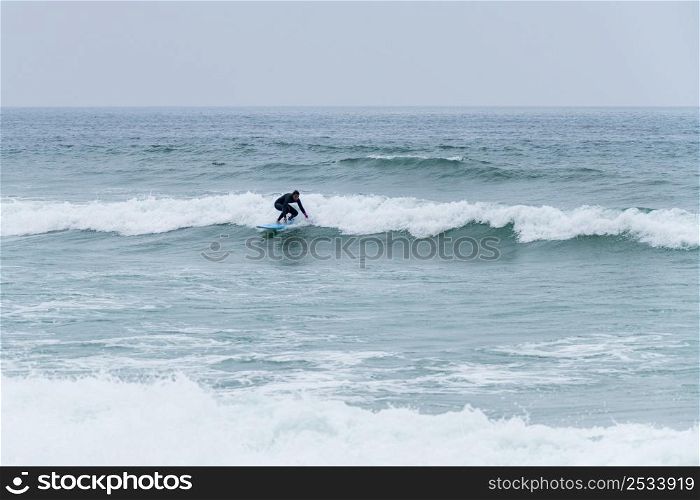 Surfer girl riding a wave with a soft board in Furadouro beach, Ovar - Portugal.