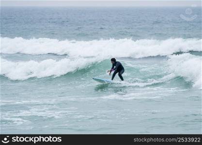 Surfer girl riding a wave with a soft board in Furadouro beach, Ovar - Portugal.