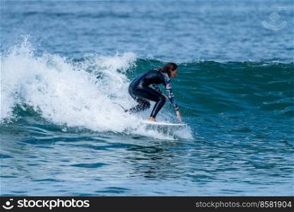 Surfer girl riding a wave with on a hot sunny day in Furadouro beach, Ovar - Portugal.