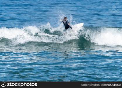 Surfer girl riding a wave with on a hot sunny day in Furadouro beach, Ovar - Portugal.