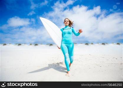 Surfer girl running at the beach with her surfboard