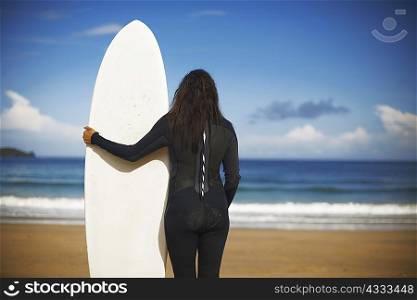 Surfer holding board on beach