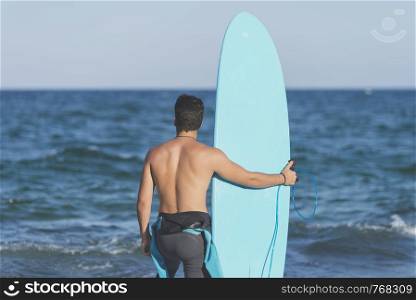 Surfer holding his blue surfboard ( LIFESTYLE )