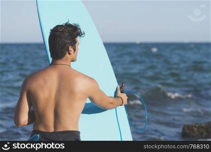 Surfer holding his blue surfboard ( LIFESTYLE )