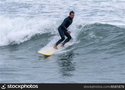 Surfer in action on the ocean waves on a cloudy morning at Furadouro beach, Ovar - Portugal.