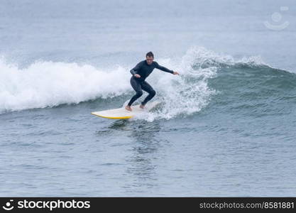 Surfer in action on the ocean waves on a cloudy morning at Furadouro beach, Ovar - Portugal.