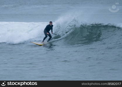 Surfer in action on the ocean waves on a cloudy morning at Furadouro beach, Ovar - Portugal.