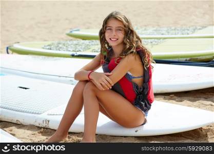 Surfer kid girl sitting in surfboard on the beach sand
