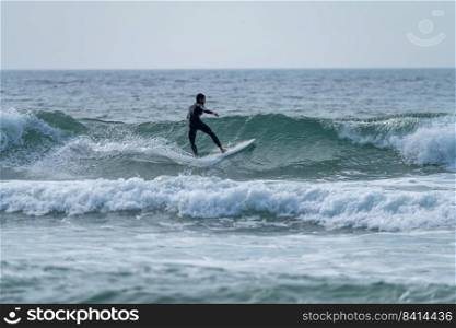 Surfer riding a wave on a cloudy afternoon at Torreira beach, Murtosa - Portugal.