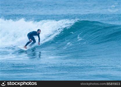Surfer riding a wave with on a foggy morning in Furadouro beach, Ovar - Portugal.