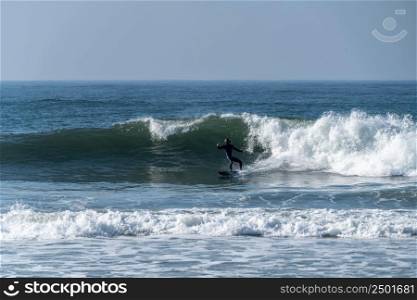 Surfer riding waves in Furadouro beach, Portugal. Men catching waves in ocean. Surfing action water board sport. Water sport lessons and beach swimming activity.