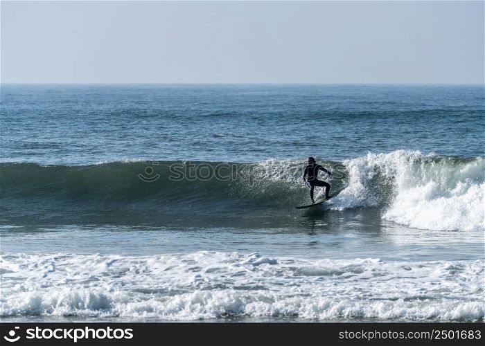 Surfer riding waves in Furadouro beach, Portugal. Men catching waves in ocean. Surfing action water board sport. Water sport lessons and beach swimming activity.
