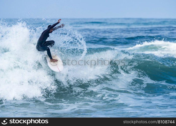 Surfer riding waves in Furadouro Beach, Portugal. Men catching waves in ocean. Surfing action water board sport. people water sport lessons and beach swimming activity on summer vacation.