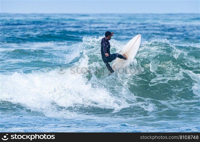 Surfer riding waves in Furadouro Beach, Portugal. Men catching waves in ocean. Surfing action water board sport. people water sport lessons and beach swimming activity on summer vacation.