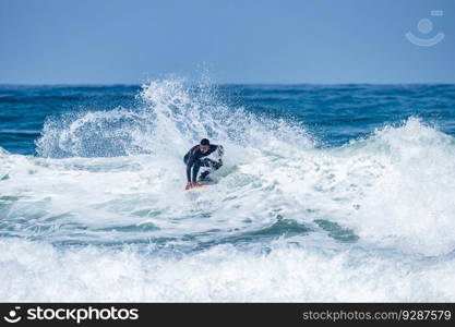 Surfer riding waves in Furadouro Beach, Portugal. Men catching waves in ocean. Surfing action water board sport. people water sport lessons and beach swimming activity on summer vacation.